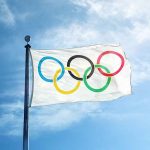 Olympic flag waving against a blue sky