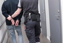 Officer escorting handcuffed person down hallway