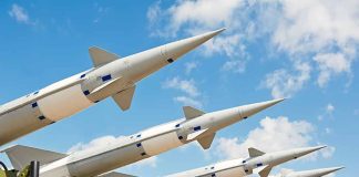 Multiple missiles pointed upward on launchers against blue sky
