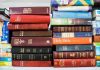 Several Bible editions stacked on a bookshelf