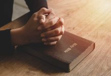 Hands praying on a Bible