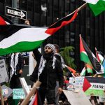 Protesters with flags and signs one holding a megaphone