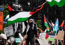 Protesters with flags and signs one holding a megaphone