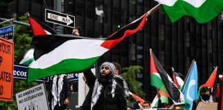 Protesters with flags and signs one holding a megaphone