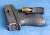 Handgun on blue fabric with visible bullet cartridge
