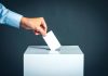 Hand placing ballot into voting box