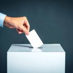 Hand placing ballot into voting box