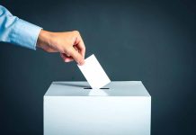 Hand placing ballot into voting box