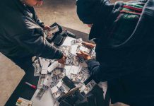 Two individuals handling stacks of money on a table