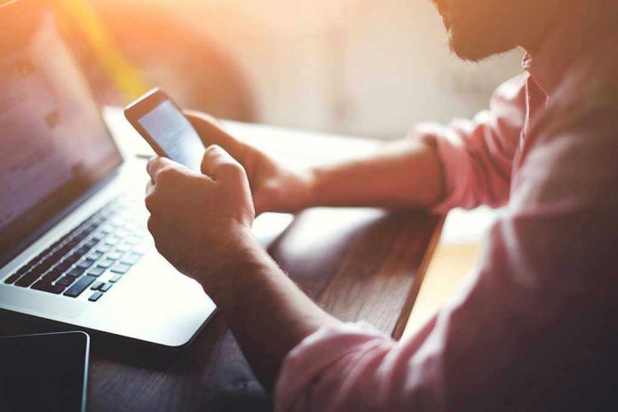 268450493 Person using a smartphone and laptop at desk