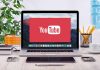 YouTube logo on a laptop screen on desk.