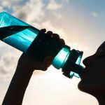Silhouette of person drinking from a water bottle