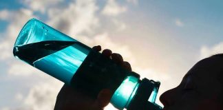 Silhouette of person drinking from a water bottle