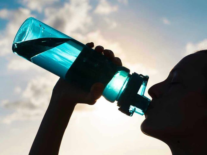 Silhouette of person drinking from a water bottle