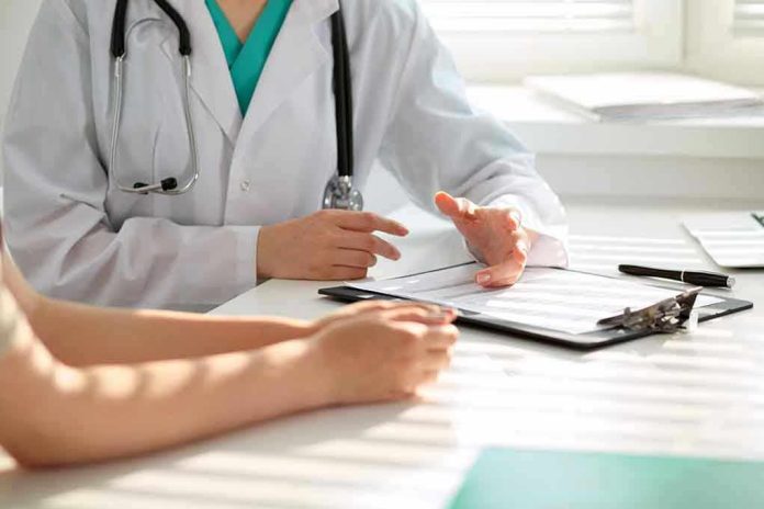 50075309 Doctor discussing with patient holding clipboard on desk