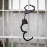 Handcuffs hanging on white metal bars