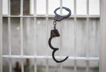 Handcuffs hanging on white metal bars