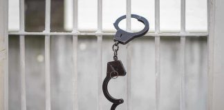 Handcuffs hanging on white metal bars