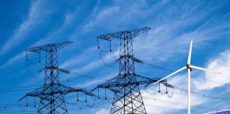 Solar panels and a wind turbine with power lines against a blue sky
