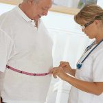 A healthcare professional measuring a patient's waist with a tape measure