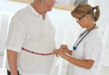 A healthcare professional measuring a patient's waist with a tape measure
