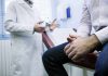 A doctor in a white coat discussing with a patient sitting on an examination table
