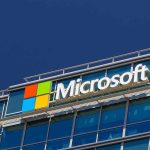 Microsoft logo on a modern corporate building against a blue sky