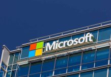 Microsoft logo on a modern corporate building against a blue sky