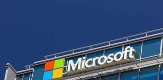 Microsoft logo on a modern corporate building against a blue sky