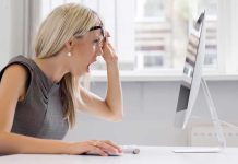 A woman with blonde hair showing a surprised expression while looking at a computer