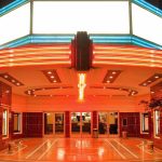 Entrance of a vintage movie theater illuminated by neon lights at night