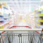 Shopping cart in aisle of grocery store.