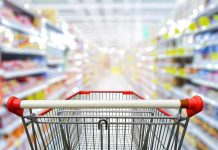 Shopping cart in aisle of grocery store.