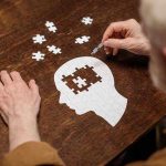 Elderly person completing head shaped jigsaw puzzle