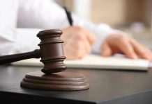 Judge's gavel on desk with person writing.
