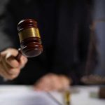 Hand holding gavel in courtroom setting