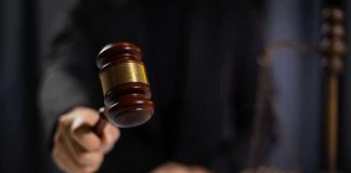 Hand holding gavel in courtroom setting
