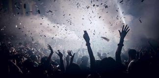 Crowd celebrating under confetti and bright lights