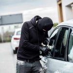 Person in black breaking into a car