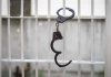 Handcuffs hanging on white metal bars.