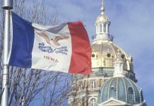 Iowa state flag waving in front of the state capitol building