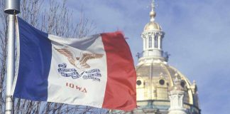 Iowa state flag waving in front of the state capitol building
