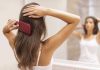 A woman brushing her long hair in front of a bathroom mirror