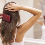 A woman brushing her long hair in front of a bathroom mirror