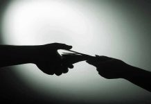 Silhouette of hands exchanging money in dim light