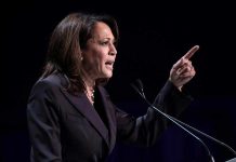 Person speaking at podium with raised finger
