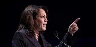 Person speaking at podium with raised finger