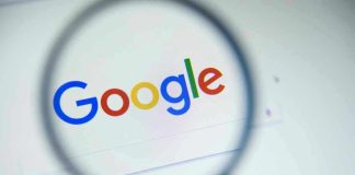 Google logo viewed through a magnifying glass.
