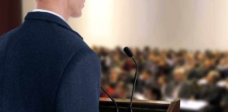 A speaker at a podium addressing an audience