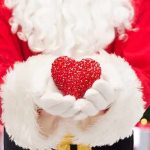 There Are Hidden Causes of Heart Attacks in Women Under 50 Santa Claus holding a red heart in front of a festive background